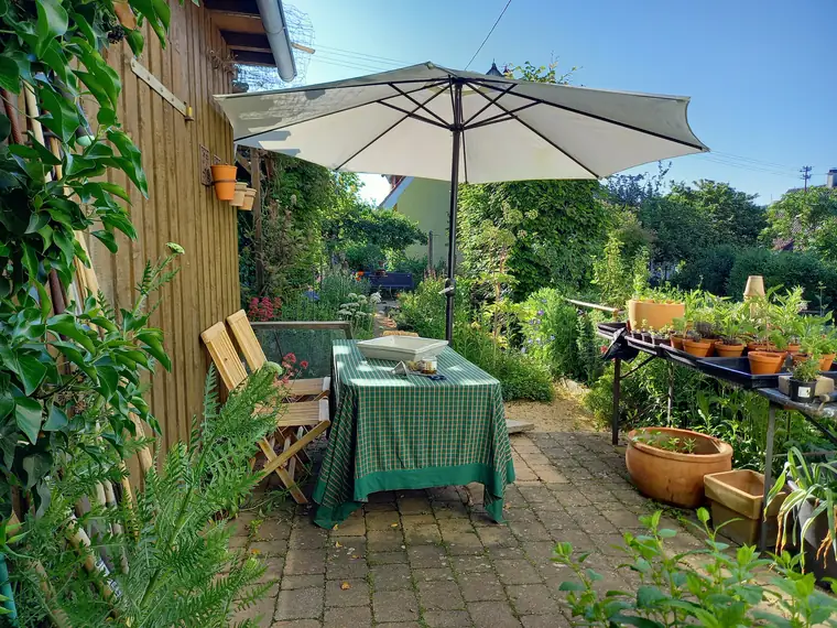 Sitzplatz mit Sonnenschirm und grün-weiß gedecktem Tisch vor dem Wagen