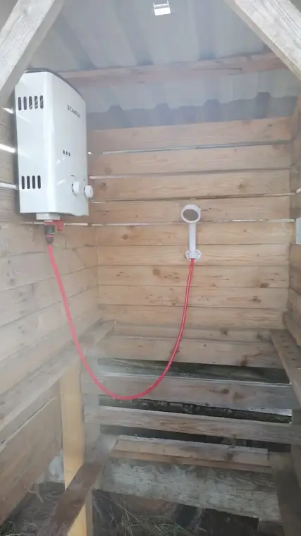 Gas-Durchlauferhitzer über der Duschbrause in der Holzkabine