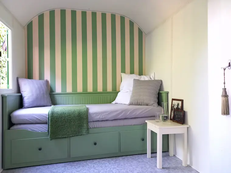 Bett mit grün-weiß gestreiftem Kopfteil, Kissen und grüner Decke