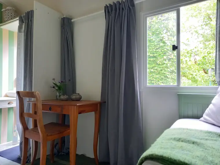Schreibtisch mit Stuhl am Fenster, Vorhang zur Seite gezogen