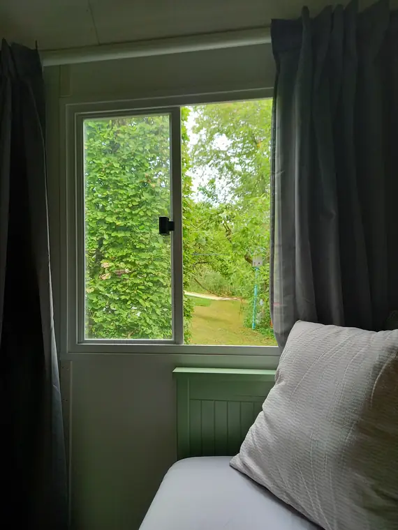 Blick aus dem Fenster ins Grüne, davor ein Kissen