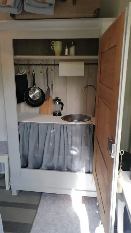 Kleines Waschbecken mit Wasserkocher und Pfanne in einer Schranknische