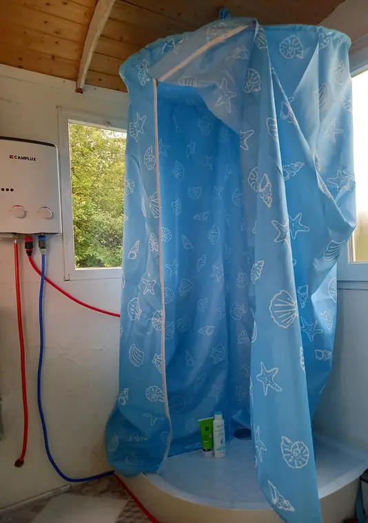 Dusche mit Vorhang und Gas-Durchlauferhitzer im Bauwagen