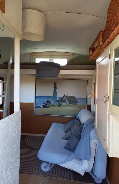 Innenraum mit Ausziehcouch, darüber das Hochbett, Wandbild mit Leuchtturm