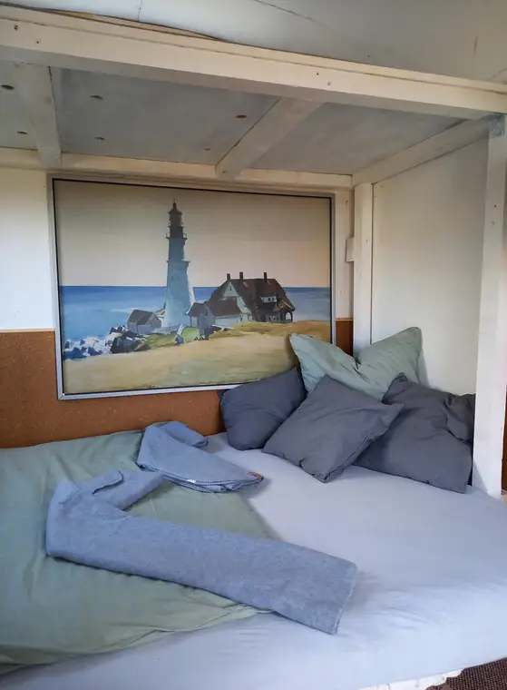 Bezogenes Bett mit Kissen und Handtüchern vor dem Wandbild