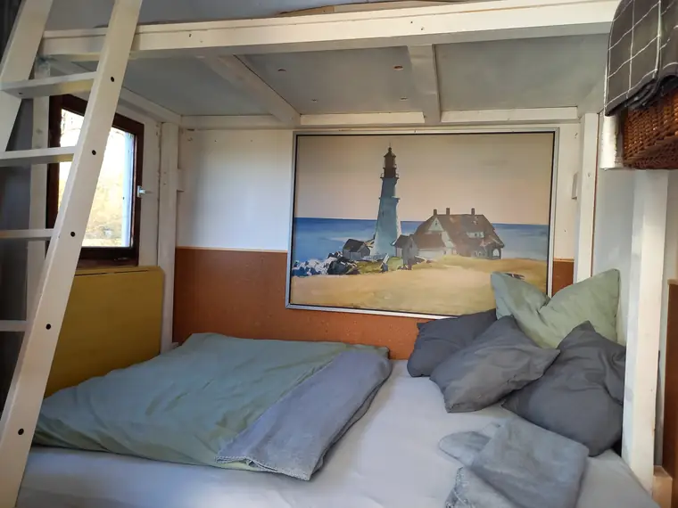 Bett im Bauwagen bei Abendlicht, Kissen und Decken aufgeschlagen