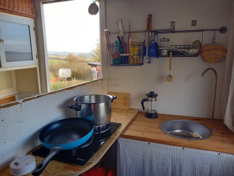 Küchenzeile mit Pfanne, Topf, Pressstempelkanne und Spüle unter dem Fenster