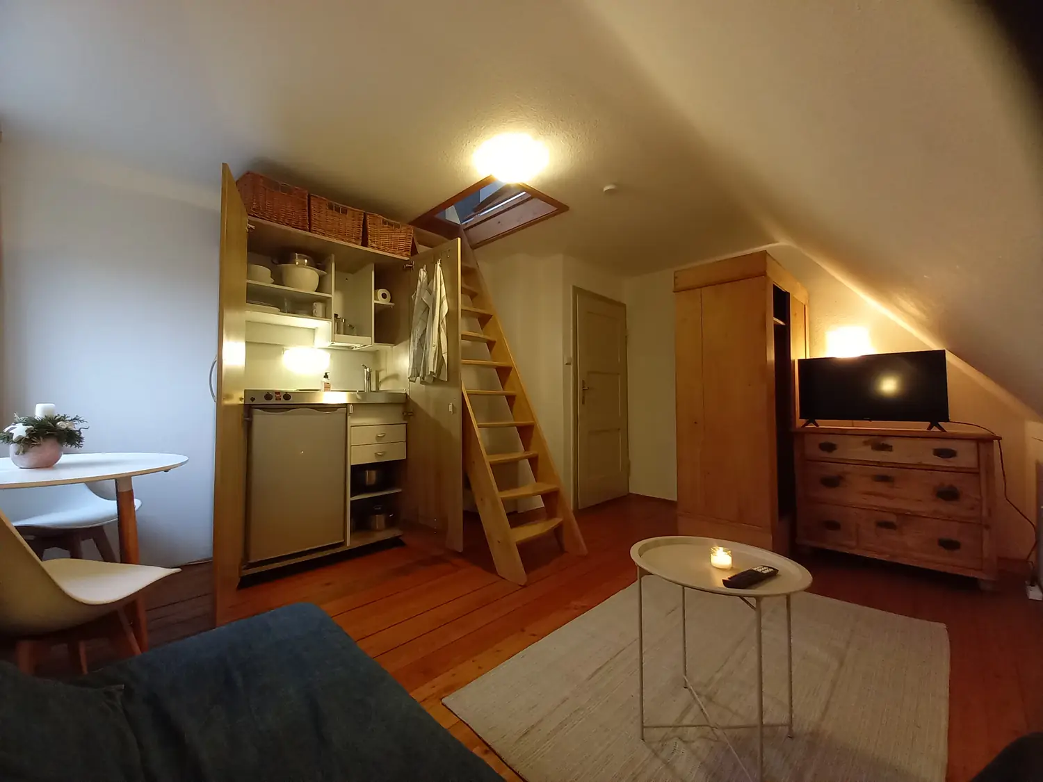 Wohnraum mit Kommode, Couch, Fernseher und Treppe zur Empore