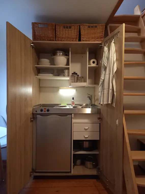 Kochnische mit Spüle, Kühlschrank, Regal und Körben