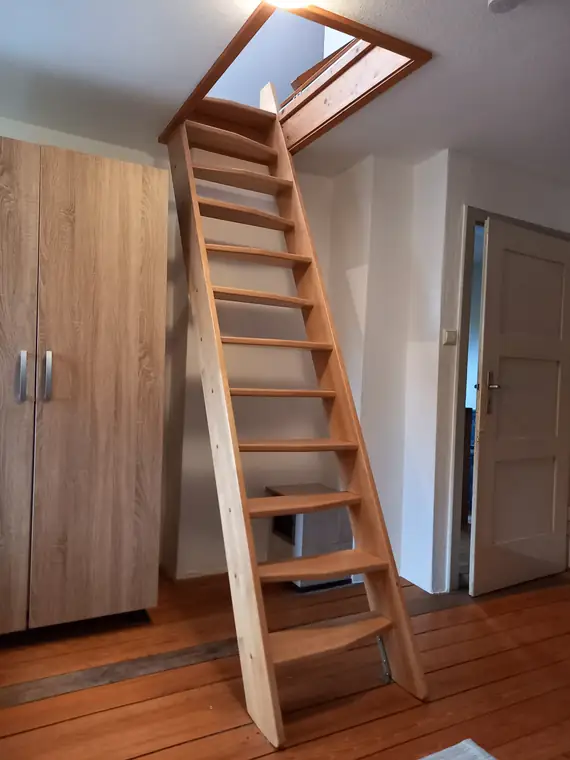 Steile Holztreppe zur Schlafempore unter dem Dachfenster