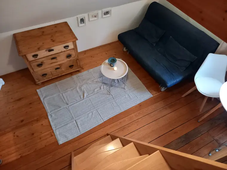 Blick von der Treppe hinunter auf Couch, Kommode und Teppich