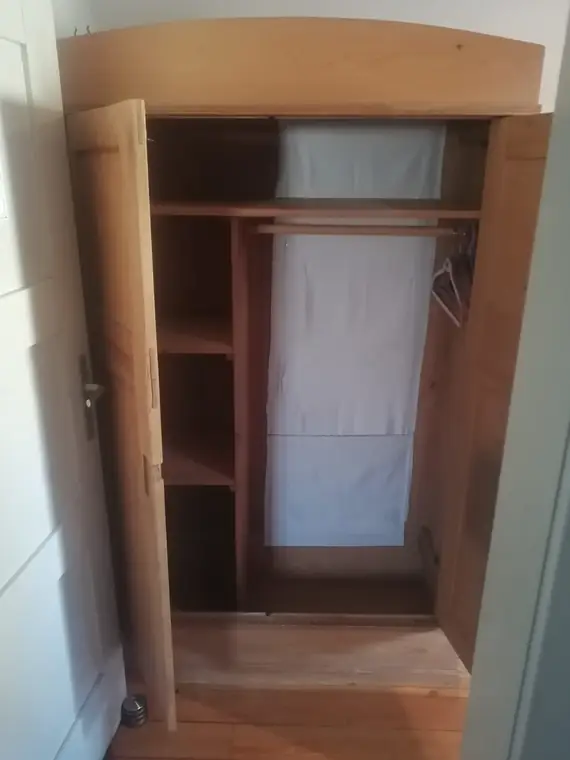 Geöffneter Kleiderschrank mit Kleiderstange und Ablage